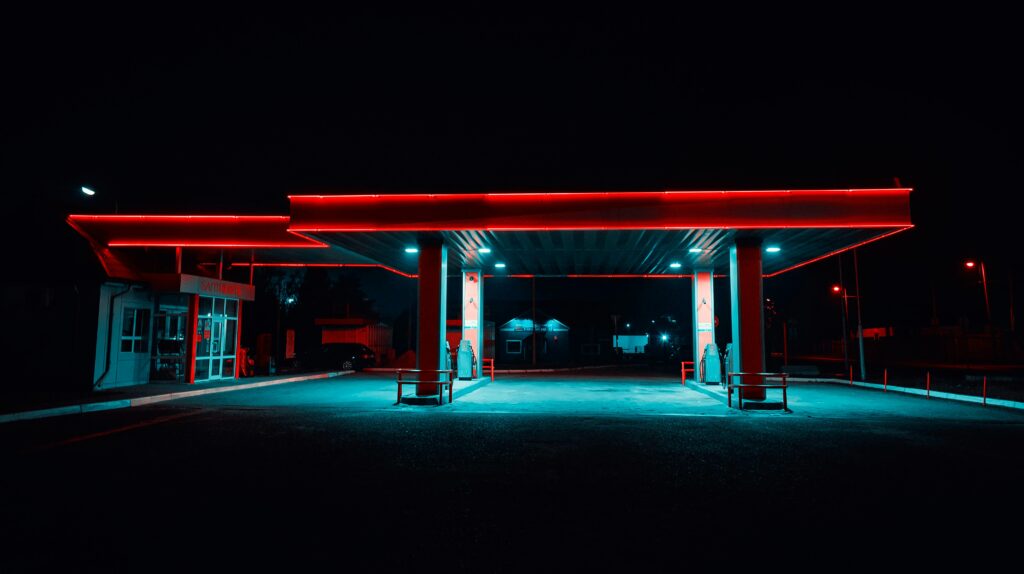 Urban gas station illuminated with vibrant neon lights at night. Modern transportation hub.